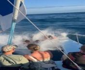 These people were on a sunset cruise on a catamaran out at sea. As they sailed out to the wind, the waves started getting taller and rocked the boat. Three women sitting on the net on the catamaran&#39;s bow had the best time as they got soaked by the crashing waves.